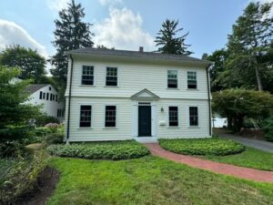 2 story house with short bushes in front of the house and a walking path leading up to the front door.